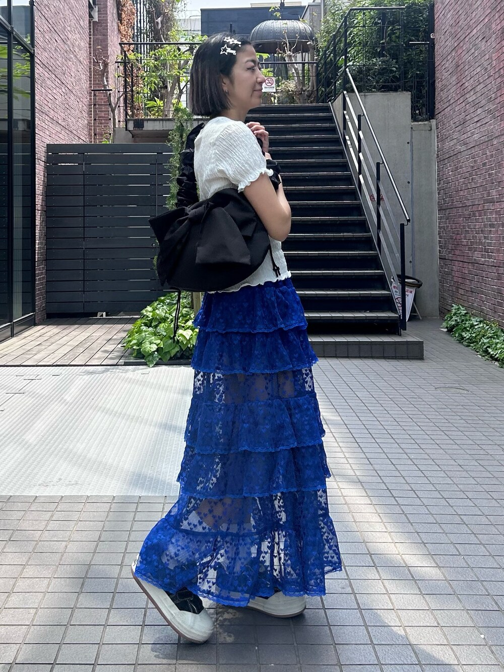 ブラック系のショルダーバッグ、ブルー系のスカート、ホワイト系のTシャツ/カットソーを着用したレディースの春コーディネートの4枚目の写真