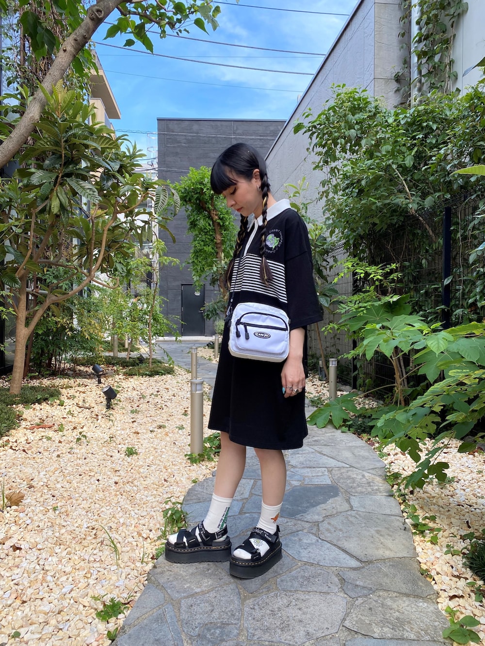 ブラック系のポロシャツ、ホワイト系のショルダーバッグを着用したレディースの夏コーディネートの3枚目の写真