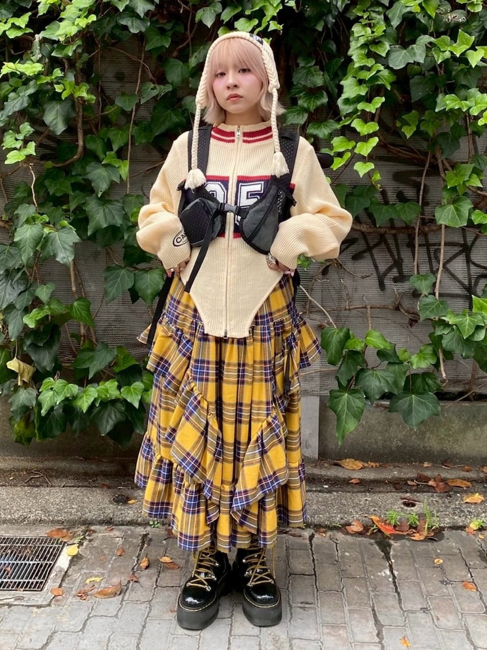 ブラック系のバックパック/リュック、イエロー系のスカート、ホワイト系のニット/セーターを着用したレディースの秋コーディネートの2枚目の写真