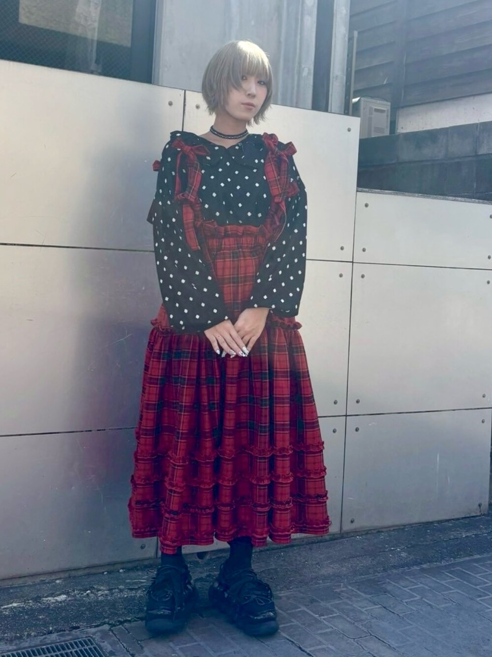 レッド系のジャンパースカート、ブラック系のニット/セーター、ブラック系のテーラードジャケットを着用したレディースの秋コーディネートの5枚目の写真