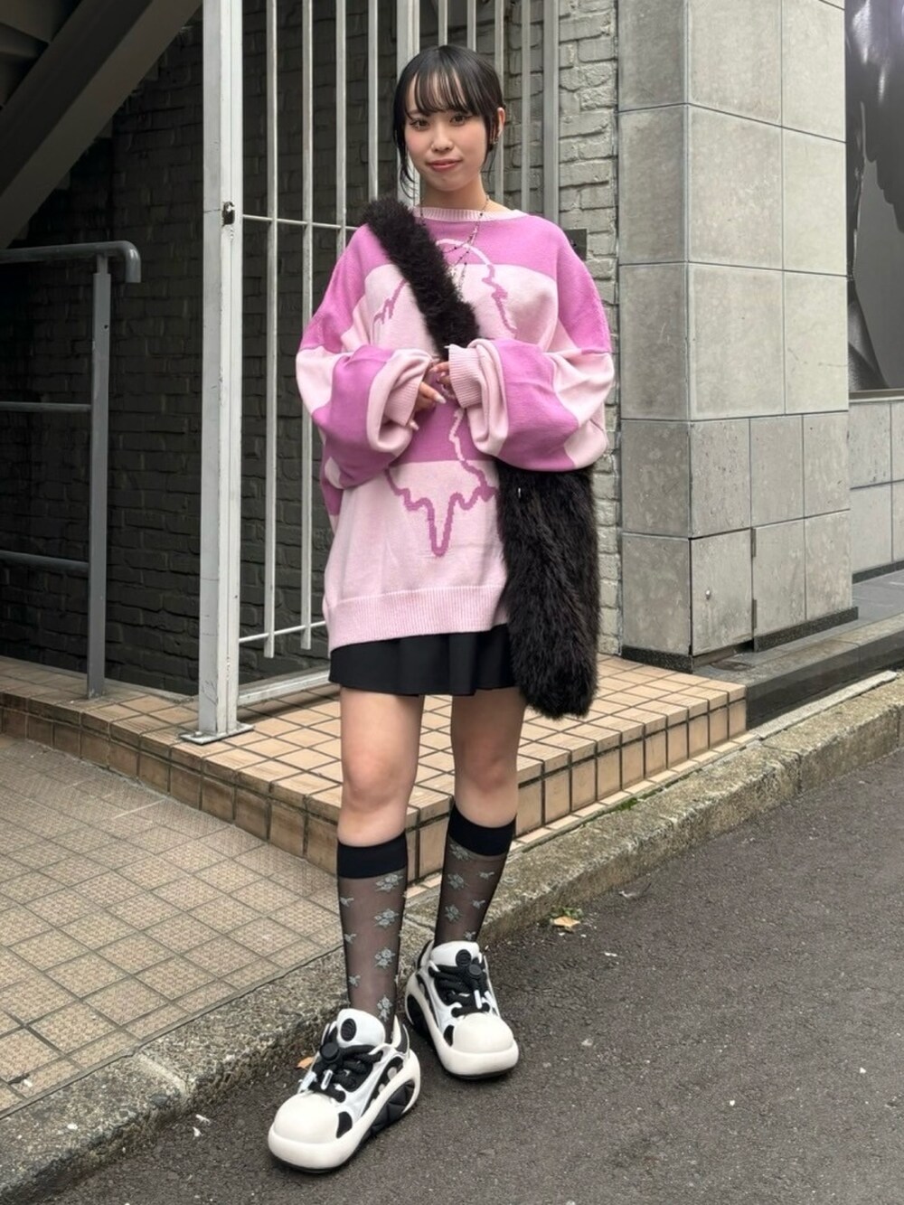 ブラック系のショルダーバッグ、ブラック系のスカート、ピンク系のニット/セーターを着用したレディースの秋コーディネートの2枚目の写真