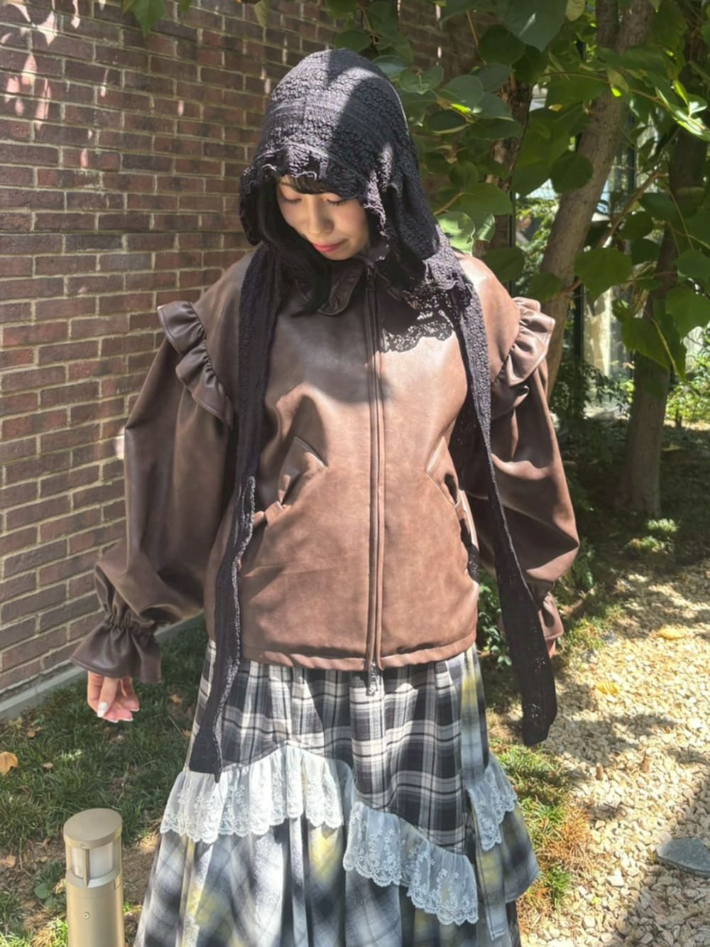 ブラウン系のライダースジャケット、イエロー系のスカート、ブラウン系のブーツを着用したレディースの冬コーディネートの3枚目の写真