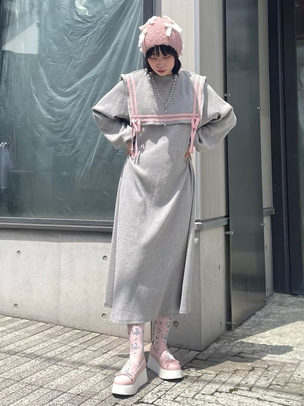 グレー系のワンピース、ピンク系のバレエシューズ、ピンク系のニットキャップ/ビーニーを着用したレディースの秋コーディネートの2枚目の写真