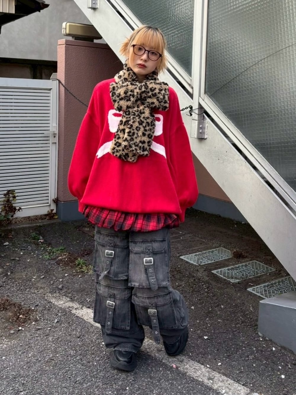 ブラック系のデニムパンツ、レッド系のスカート、レッド系のニット/セーターを着用したレディースの冬コーディネートの2枚目の写真