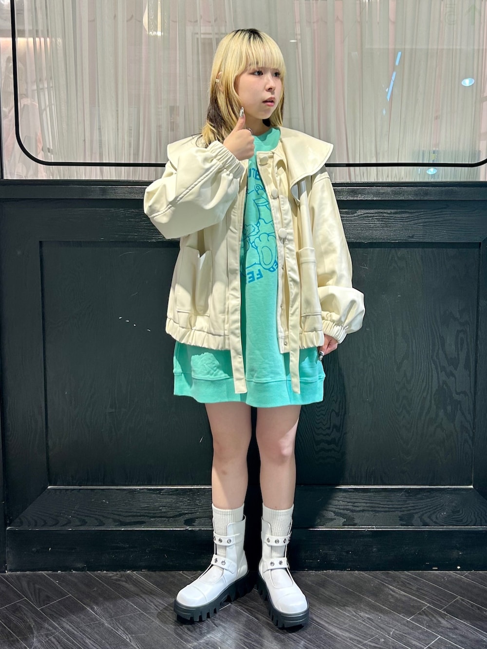 ホワイト系のライダースジャケット、グリーン系のスウェット、ホワイト系のブーツを着用したレディースの秋コーディネートの2枚目の写真