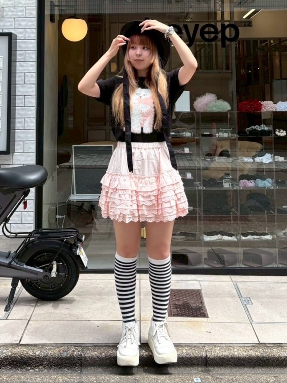 ピンク系のスカート、ブラック系のニット/セーター、ブラック系のハットを着用したレディースの夏コーディネートの2枚目の写真