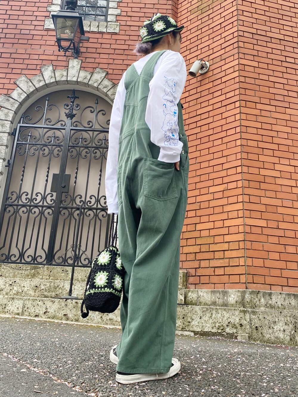 ブラック系のスニーカー、グリーン系のサロペット/オーバーオール、ホワイト系のTシャツ/カットソーを着用したレディースの春コーディネートの2枚目の写真