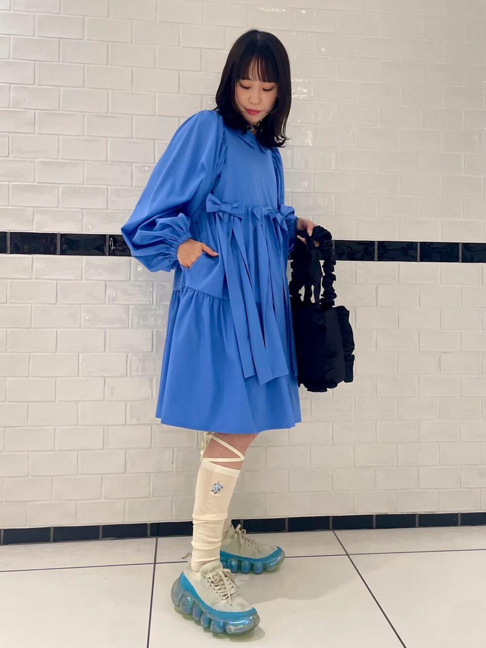 ブラック系のハンドバッグ、ブルー系のワンピース、ホワイト系のソックス/靴下を着用したレディースの冬コーディネートの3枚目の写真