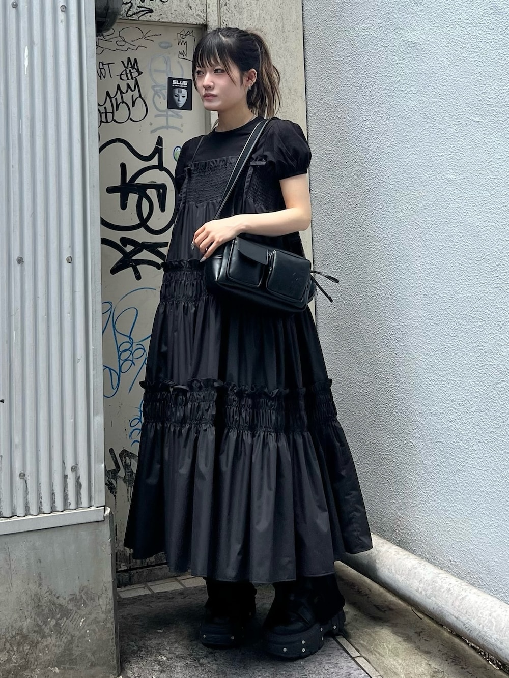 ブラック系のショルダーバッグ、ブラック系のワンピース、ブラック系のTシャツ/カットソーを着用したレディースの夏コーディネートの2枚目の写真