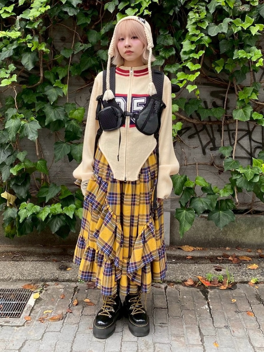 ブラック系のバックパック/リュック、イエロー系のスカート、ホワイト系のニット/セーターを着用したレディースの秋コーディネートの3枚目の写真