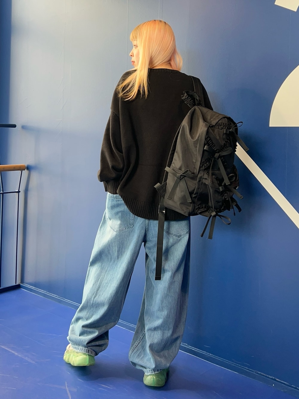 ブラック系のニット/セーター、ブルー系のデニムパンツ、ブラック系のバックパック/リュックを着用したレディースの秋コーディネートの5枚目の写真