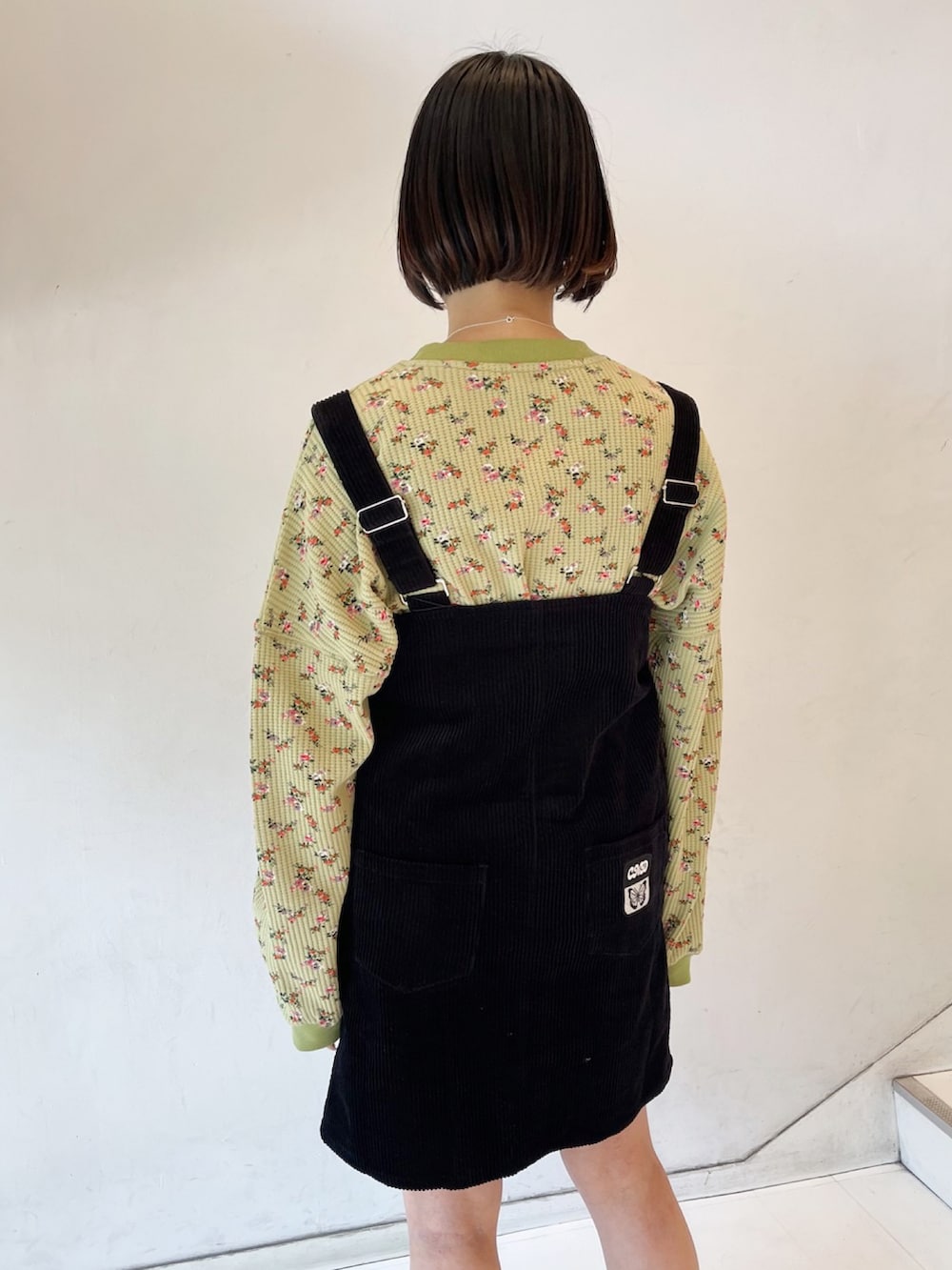 ブラック系のジャンパースカート、グリーン系のスウェット、ブラック系のスニーカーを着用したレディースの春コーディネートの3枚目の写真