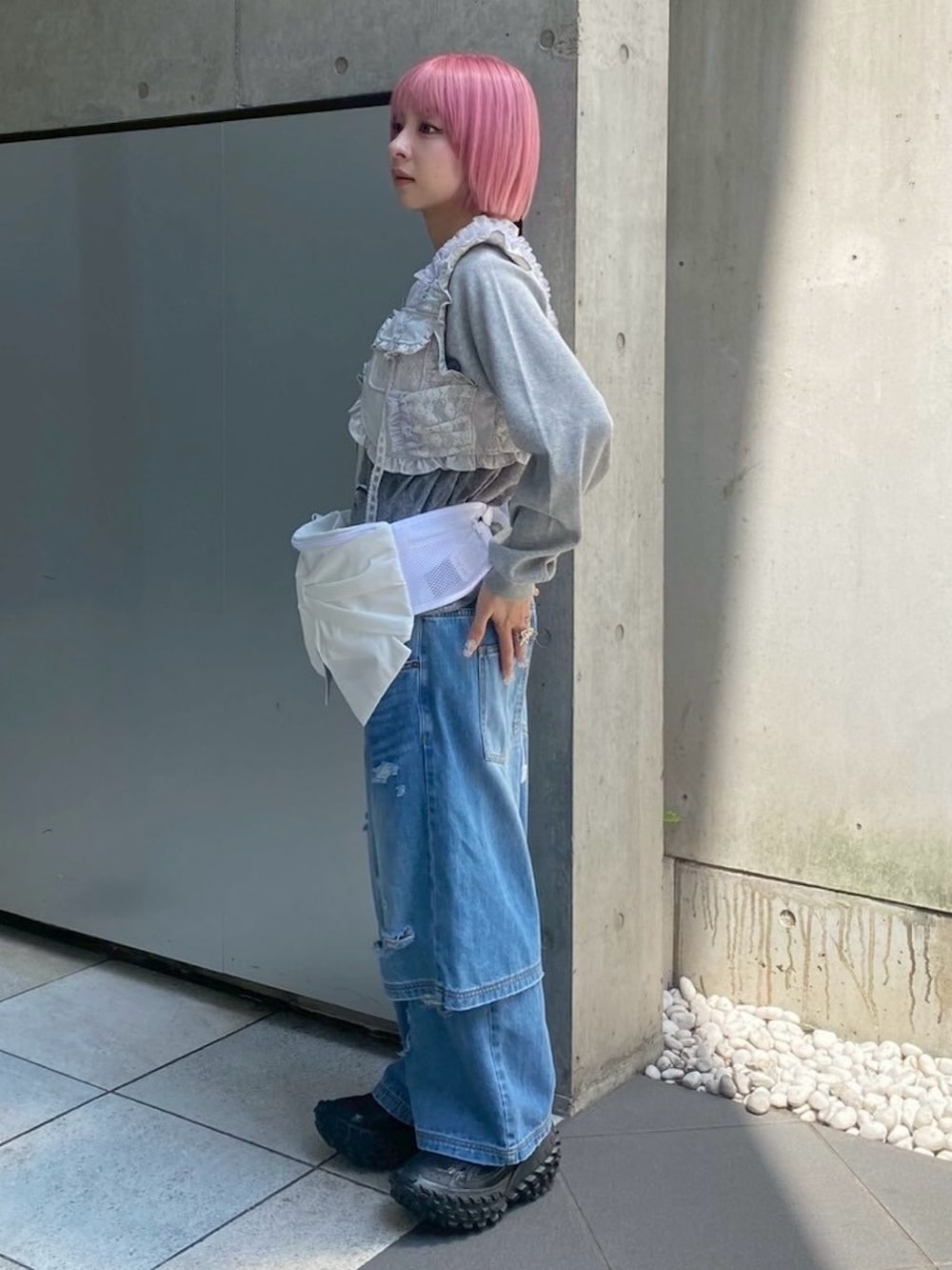 ブルー系のデニムパンツ、ホワイト系のボディバッグ/ウエストポーチ、グレー系のベストを着用したレディースの秋コーディネートの3枚目の写真