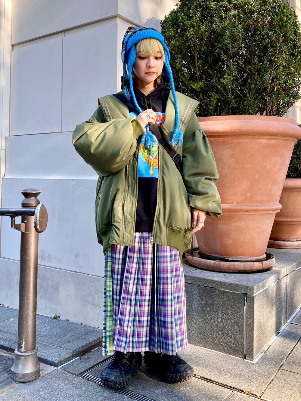 パープル系のスカート、グリーン系のMA-1、ブラック系のパーカーを着用したレディースの冬コーディネートの2枚目の写真