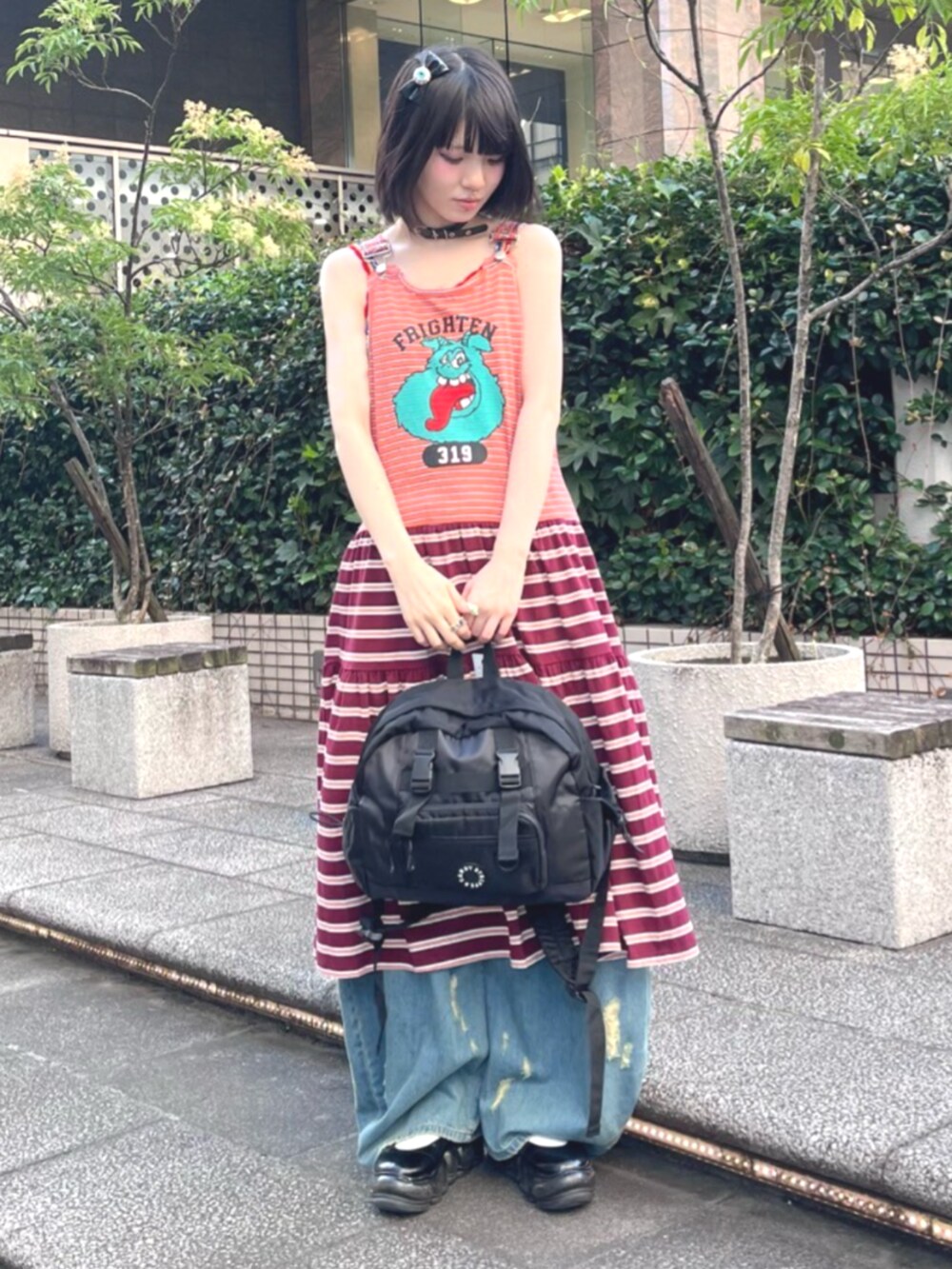 ブルー系のデニムパンツ、ブラック系のバックパック/リュック、オレンジ系のワンピースを着用したレディースの夏コーディネートの2枚目の写真