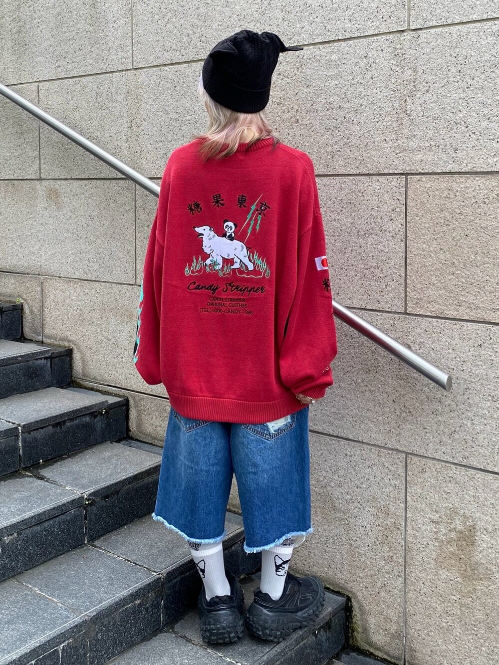 ブルー系のデニムパンツ、レッド系のニット/セーター、ブラック系のニットキャップ/ビーニーを着用したレディースの秋コーディネートの5枚目の写真