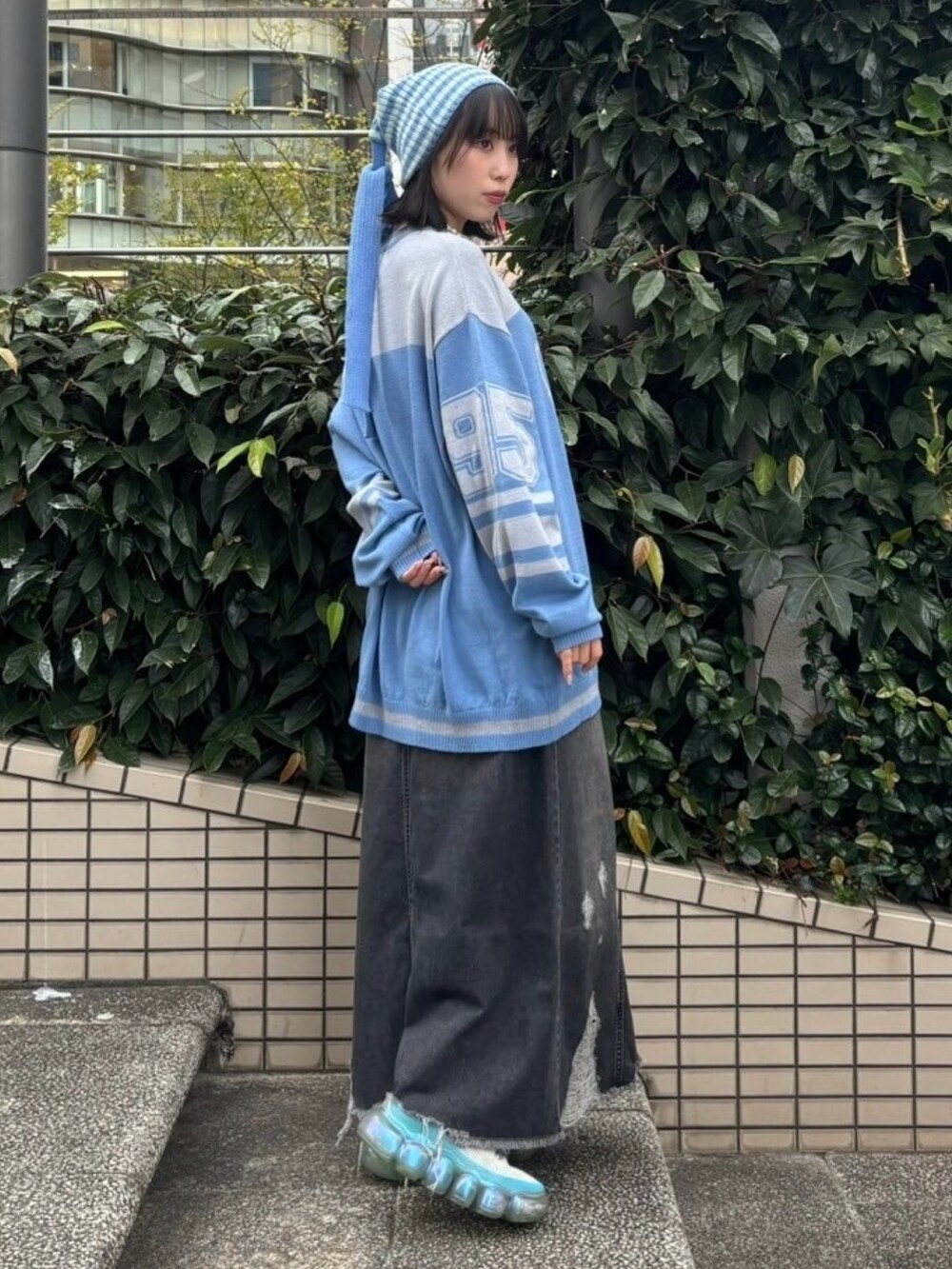 ブラック系のデニムスカート、ブルー系のニット/セーター、グリーン系のニットキャップ/ビーニーを着用したレディースの冬コーディネートの3枚目の写真