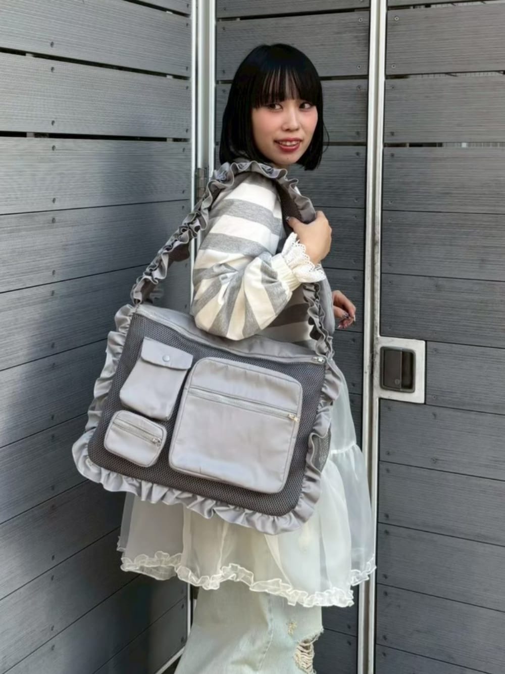 グレー系のワンピース、ブルー系のデニムパンツを着用したレディースの春コーディネートの4枚目の写真