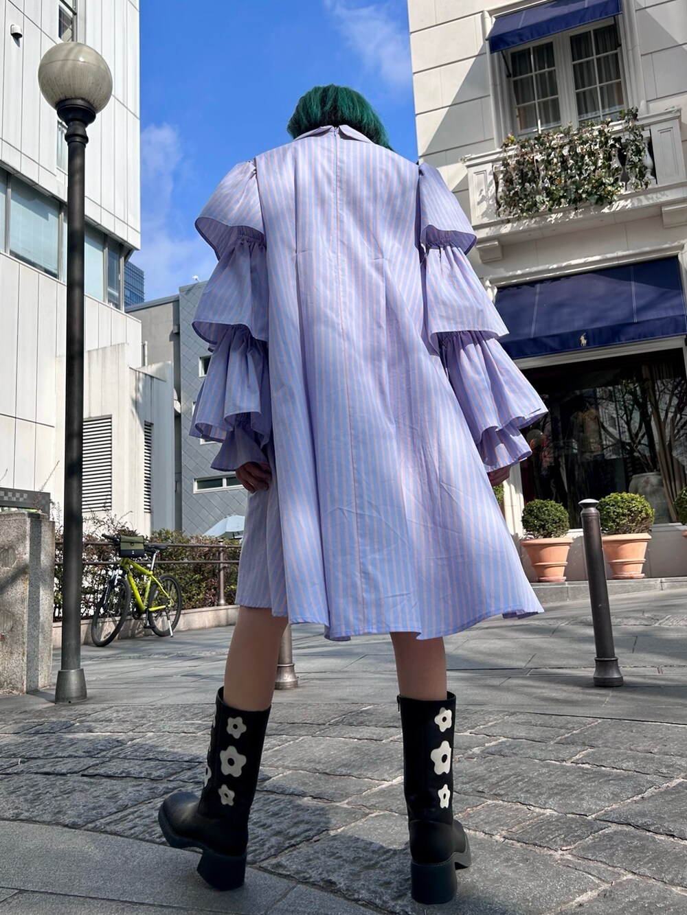 ベージュ系のトレンチコート、ブルー系のワンピース、ブラック系のブーツを着用したレディースの冬コーディネートの5枚目の写真