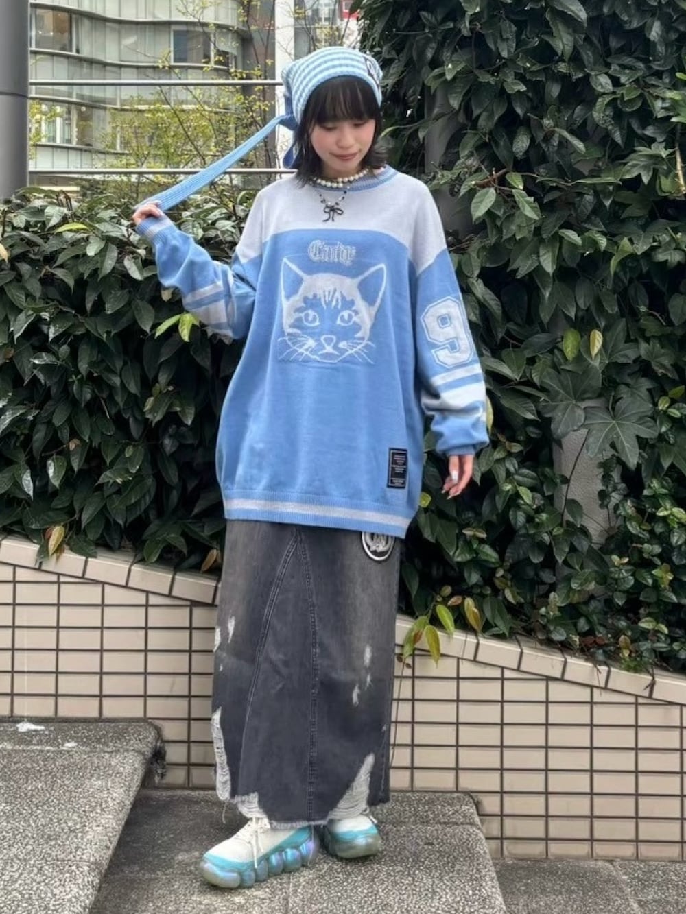 ブラック系のデニムスカート、ブルー系のニット/セーター、グリーン系のニットキャップ/ビーニーを着用したレディースの冬コーディネートの2枚目の写真