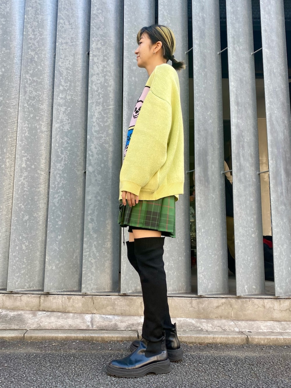 イエロー系のニット/セーター、グリーン系のスカートを着用したレディースの秋コーディネートの3枚目の写真