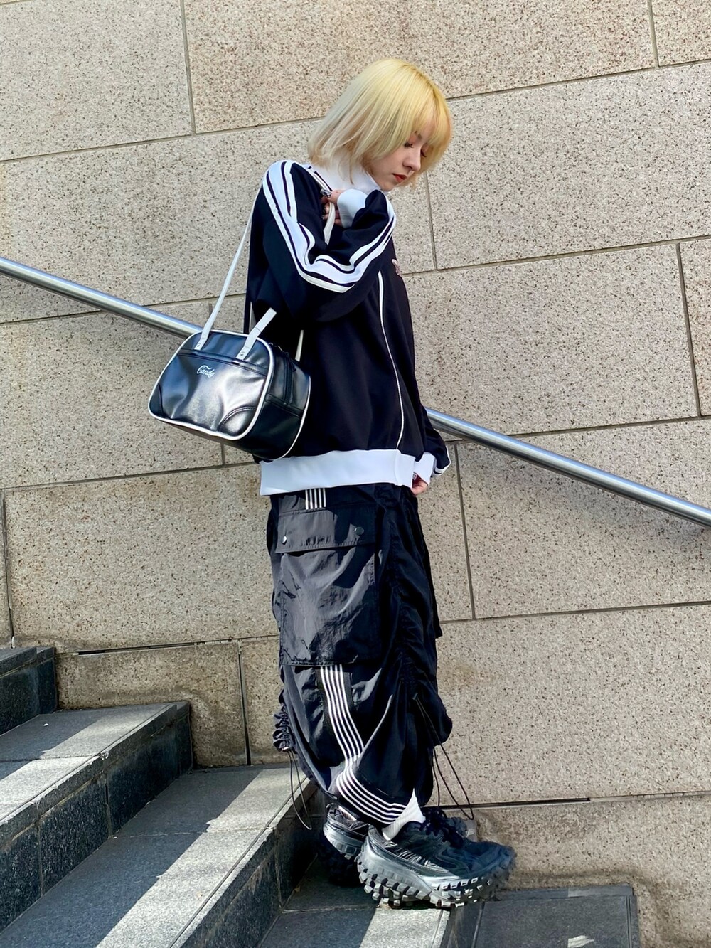 ブラック系のブルゾン、ブラック系のスカート、ブラック系のボストンバッグを着用したレディースの冬コーディネートの3枚目の写真