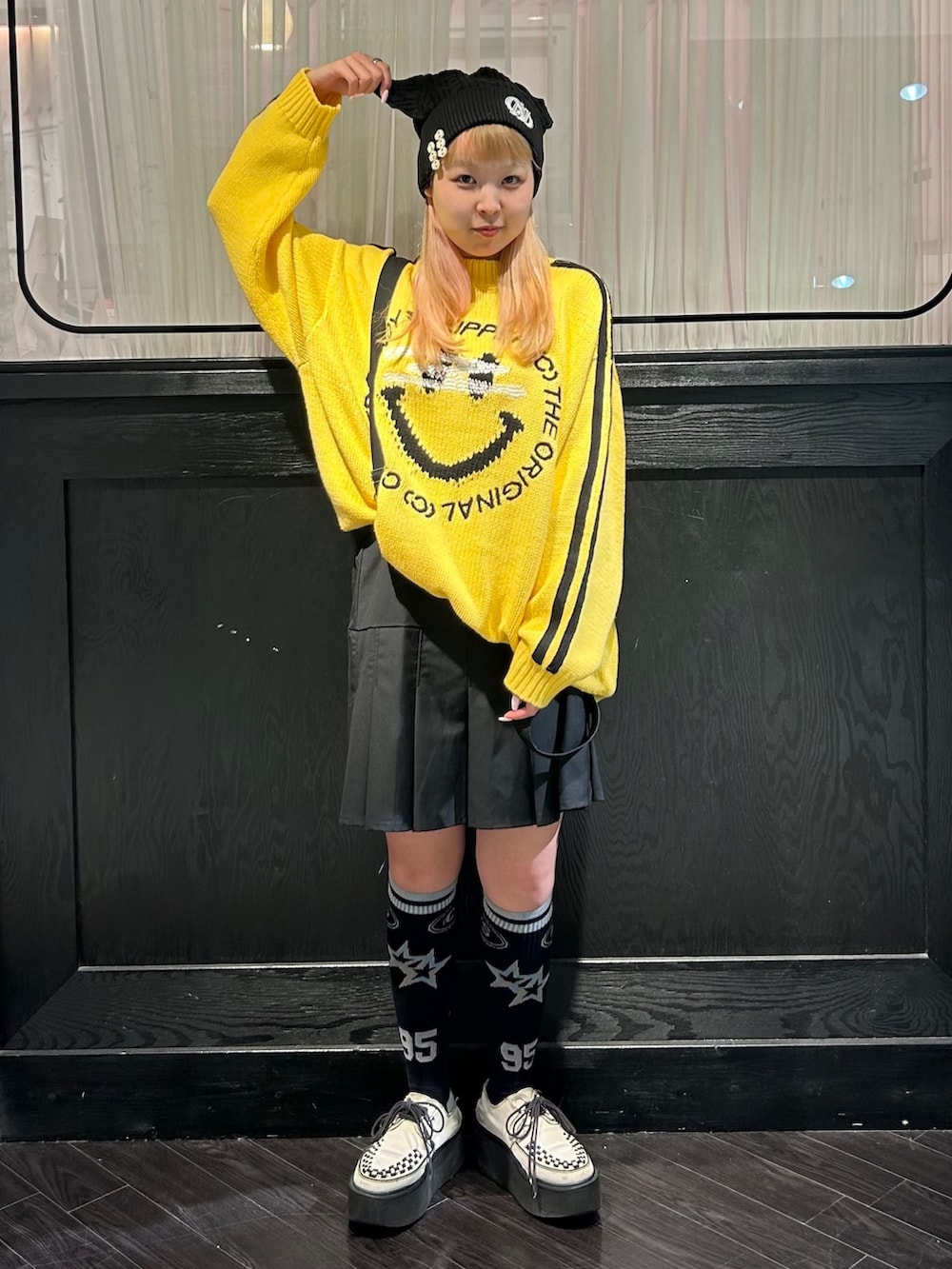 イエロー系のニット/セーター、ブラック系のスカート、ブラック系のニットキャップ/ビーニーを着用したレディースの秋コーディネートの2枚目の写真