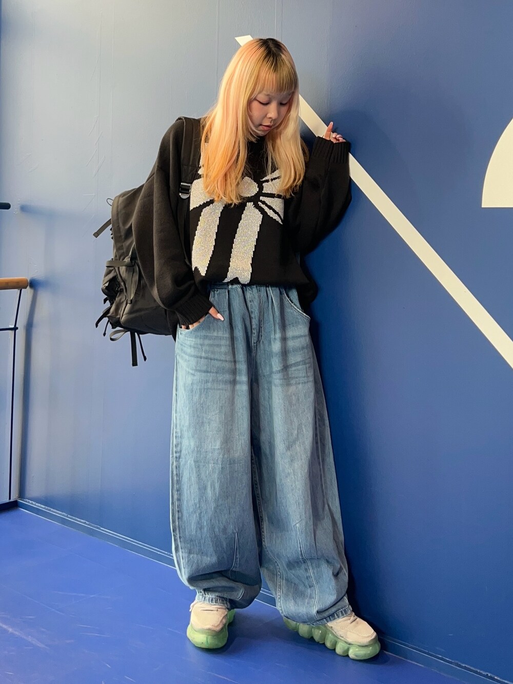 ブラック系のニット/セーター、ブルー系のデニムパンツ、ブラック系のバックパック/リュックを着用したレディースの秋コーディネートの2枚目の写真