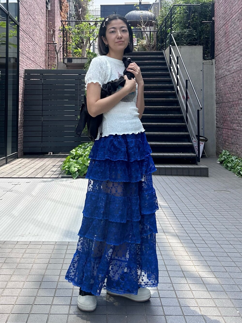 ブラック系のショルダーバッグ、ブルー系のスカート、ホワイト系のTシャツ/カットソーを着用したレディースの春コーディネートの3枚目の写真
