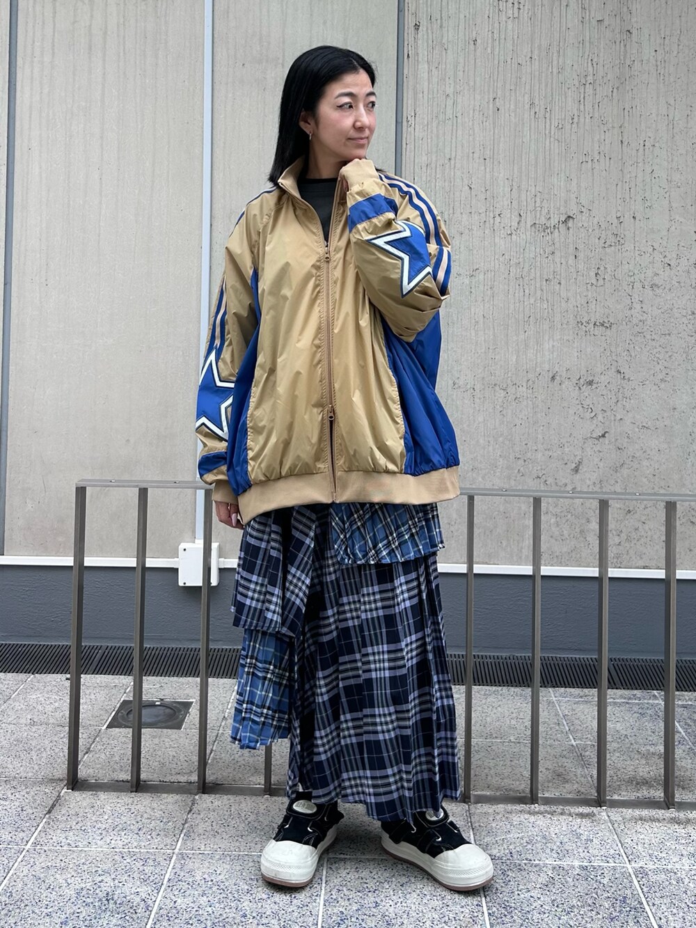 ブルー系のスカート、グレー系のTシャツ/カットソー、ベージュ系のナイロンジャケットを着用したレディースの秋コーディネートの4枚目の写真