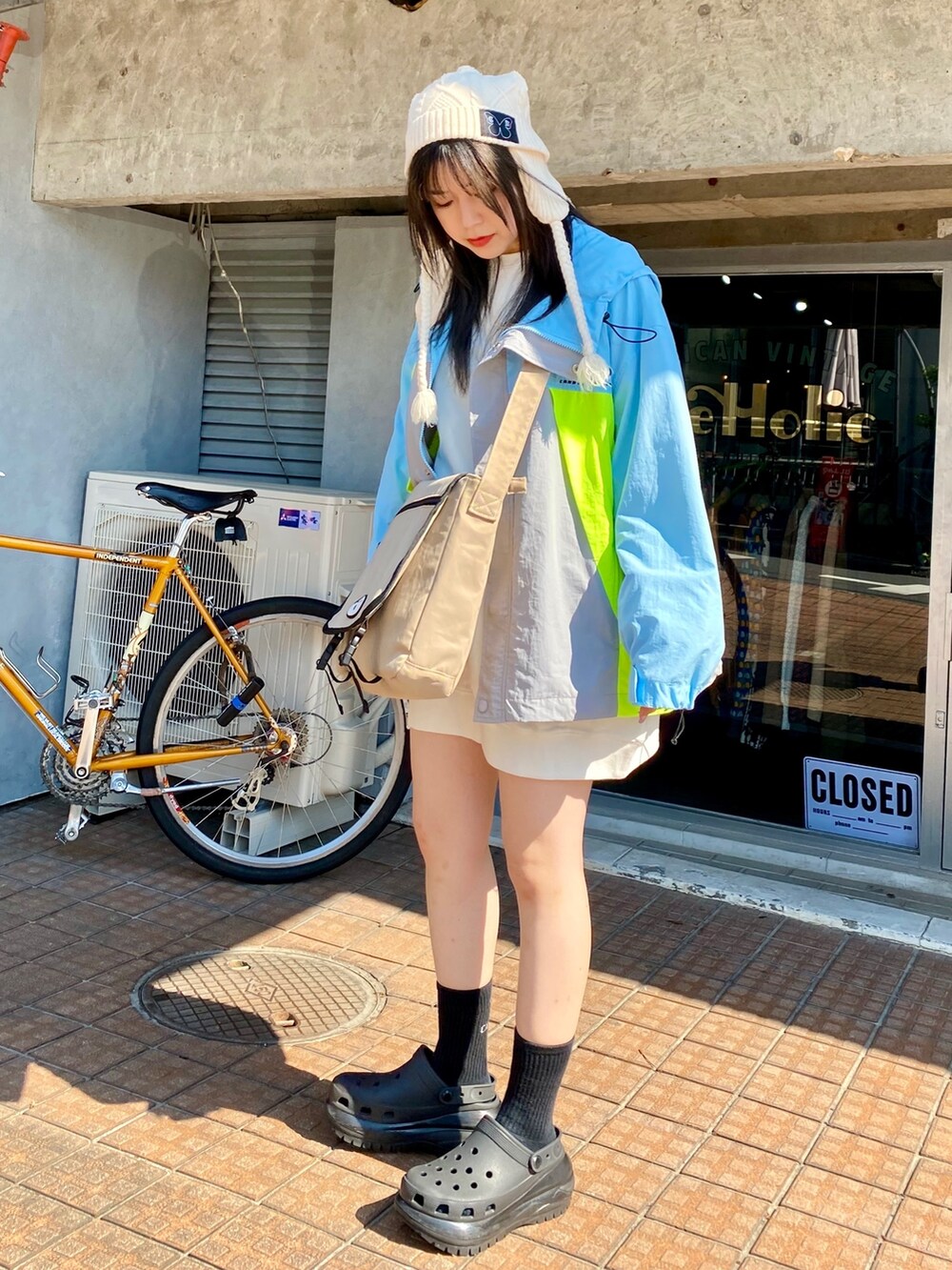 ブルー系のナイロンジャケット、ホワイト系のスウェット、ベージュ系のショルダーバッグを着用したレディースの秋コーディネートの2枚目の写真