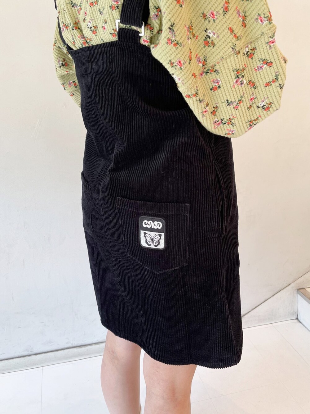 ブラック系のジャンパースカート、グリーン系のスウェット、ブラック系のスニーカーを着用したレディースの春コーディネートの4枚目の写真