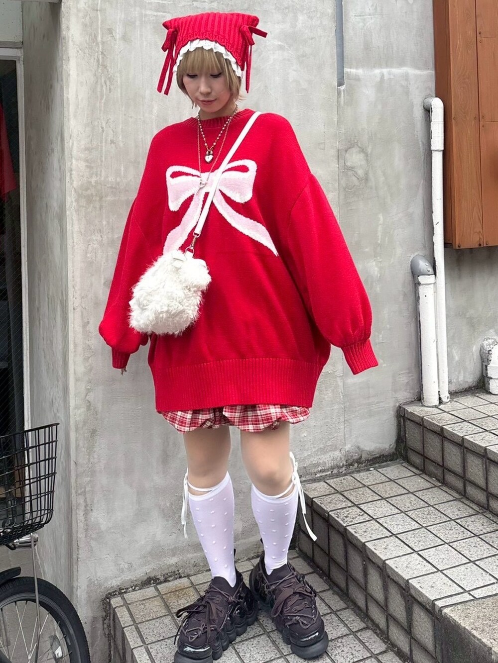 レッド系のニット/セーター、レッド系のスカート、ホワイト系のショルダーバッグを着用したレディースの秋コーディネートの3枚目の写真