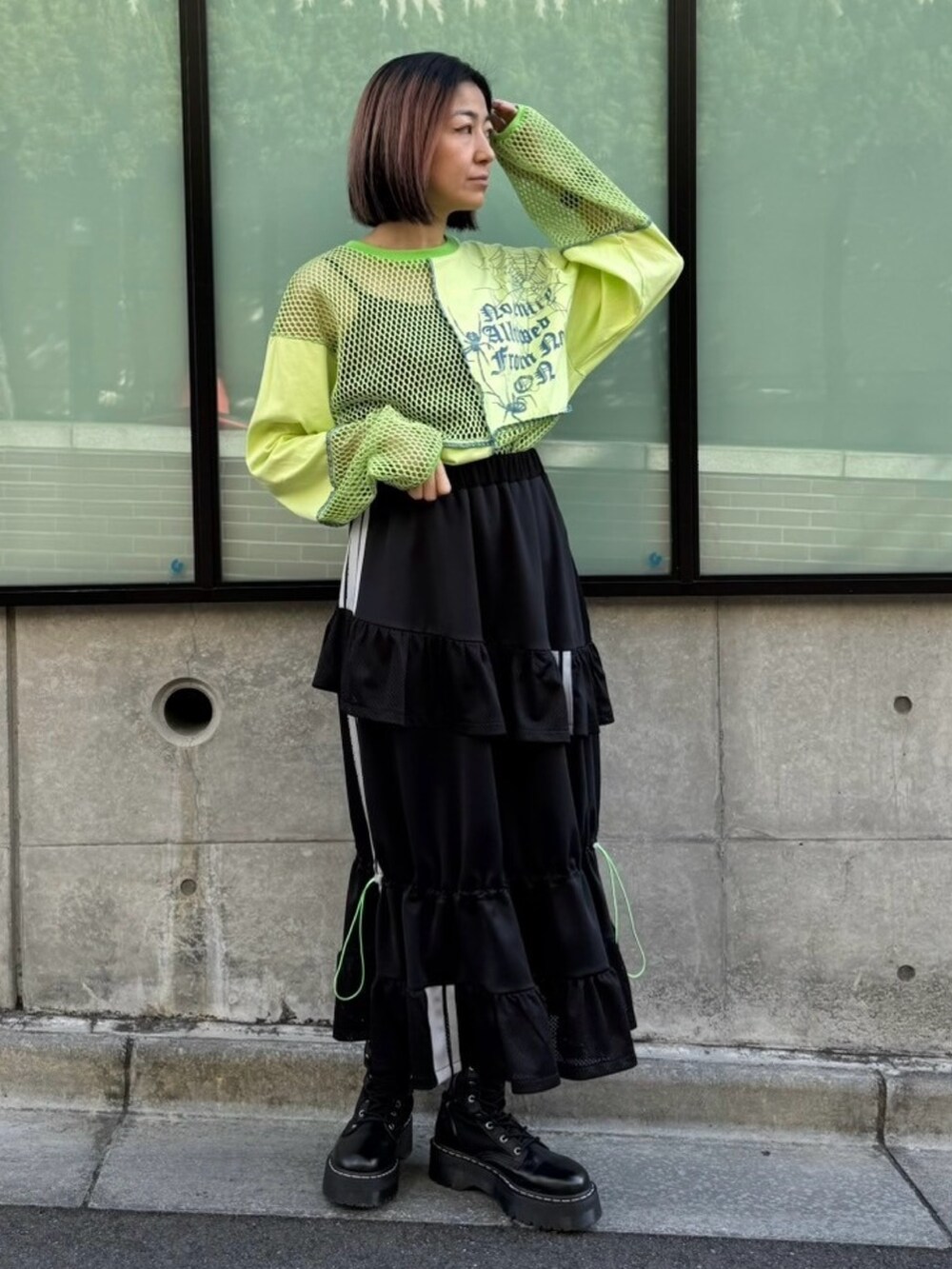グリーン系のTシャツ/カットソー、ブラック系のスカートを着用したレディースの春コーディネートの3枚目の写真