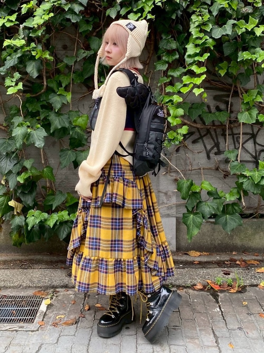 ブラック系のバックパック/リュック、イエロー系のスカート、ホワイト系のニット/セーターを着用したレディースの秋コーディネートの4枚目の写真
