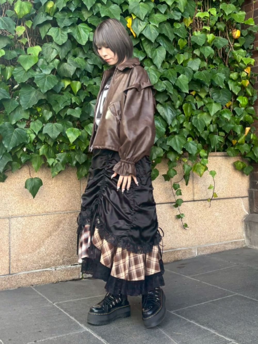 ブラウン系のライダースジャケット、ブラック系のワンピース、レッド系のスカートを着用したレディースの冬コーディネートの3枚目の写真