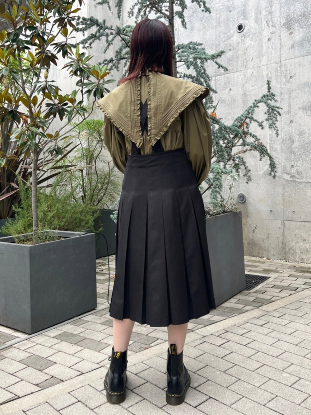 グリーン系のワンピース、ブラック系のスカート、ブラック系のシューズを着用したレディースの秋コーディネートの2枚目の写真