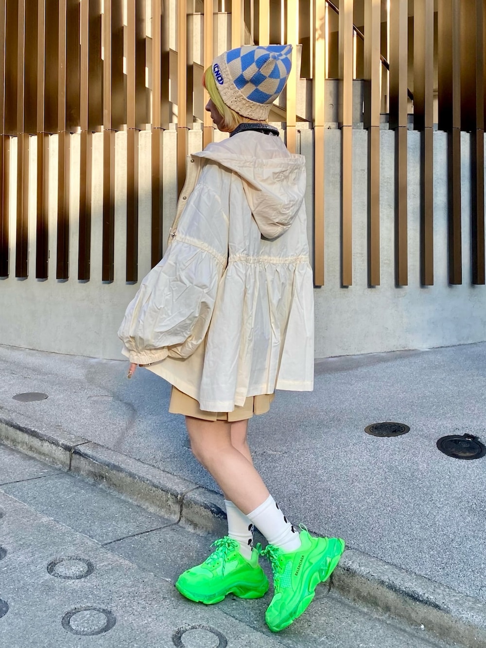 ベージュ系のナイロンジャケット、ブラック系のポロシャツ、ベージュ系のスカートを着用したレディースの春コーディネートの3枚目の写真