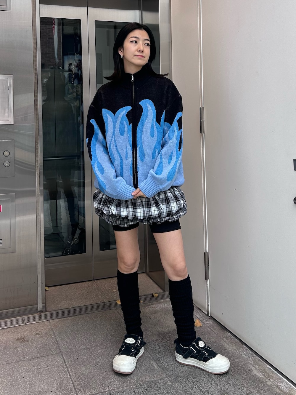 グレー系のスカート、ブラック系のニット/セーター、ブラック系のソックス/靴下を着用したレディースの秋コーディネートの3枚目の写真