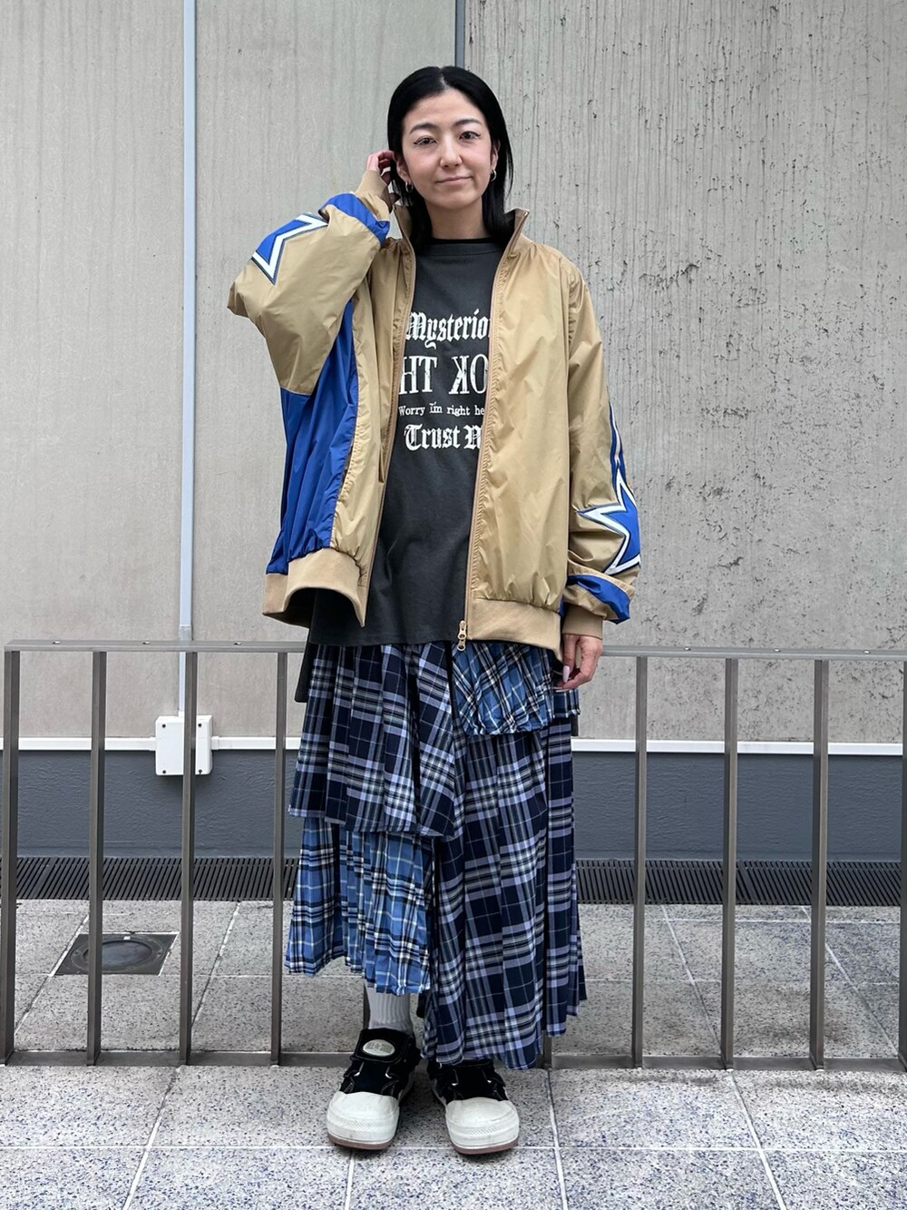 ブルー系のスカート、グレー系のTシャツ/カットソー、ベージュ系のナイロンジャケットを着用したレディースの秋コーディネートの2枚目の写真