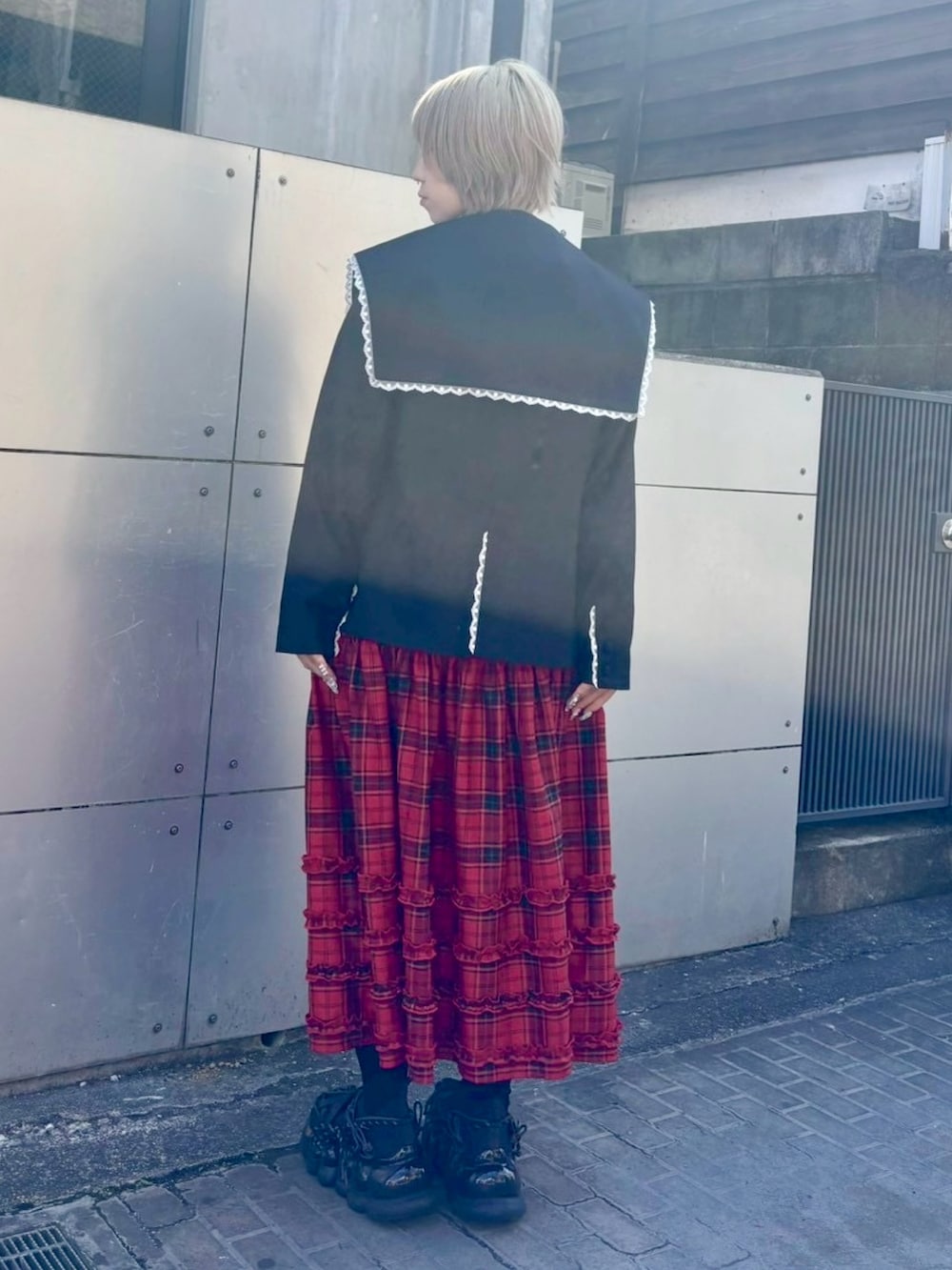 レッド系のジャンパースカート、ブラック系のニット/セーター、ブラック系のテーラードジャケットを着用したレディースの秋コーディネートの3枚目の写真