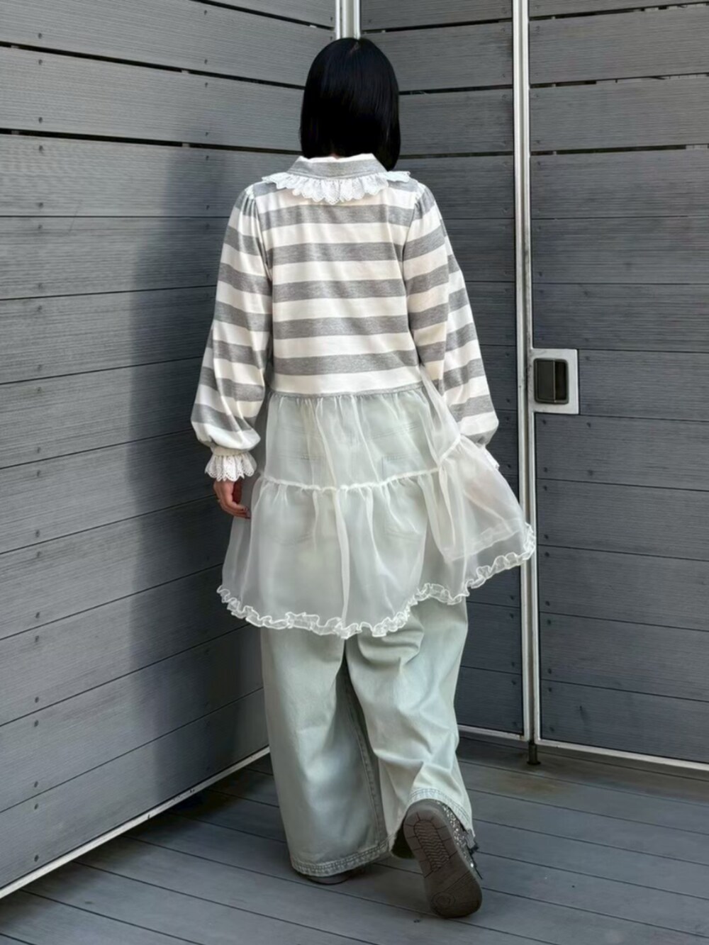 グレー系のワンピース、ブルー系のデニムパンツを着用したレディースの春コーディネートの3枚目の写真