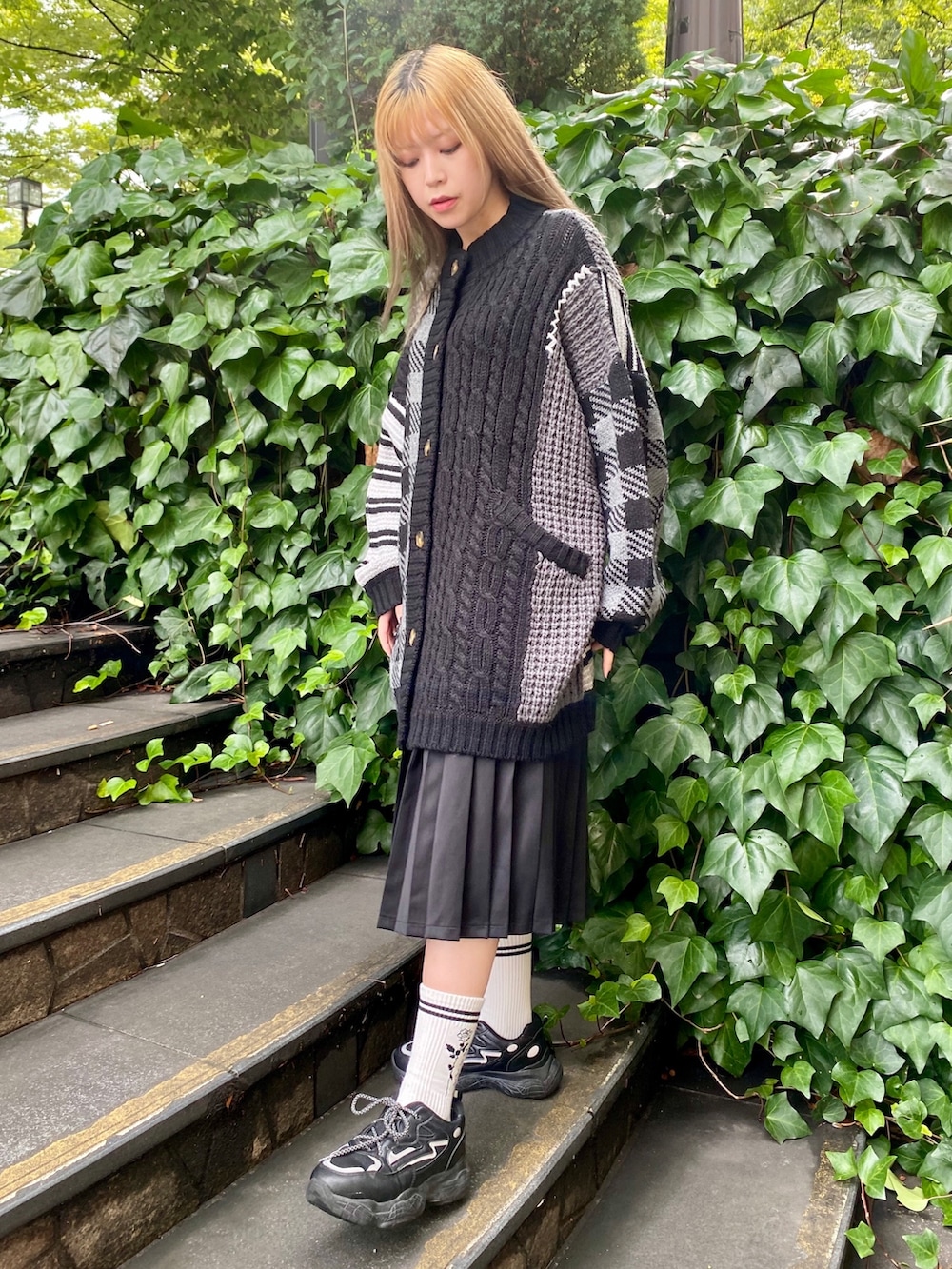 グレー系のカーディガン/ボレロ、ブラック系のスカートを着用したレディースの秋コーディネートの2枚目の写真