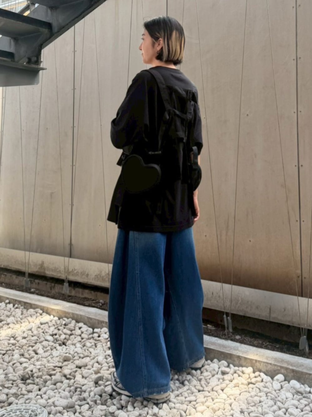 ブルー系のデニムパンツ、ブラック系のボディバッグ/ウエストポーチ、ブラック系のTシャツ/カットソーを着用したレディースの夏コーディネートの3枚目の写真