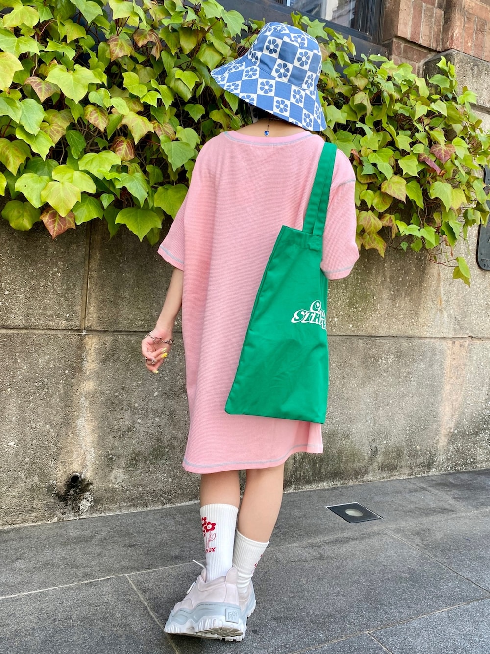 ピンク系のTシャツ/カットソー、グリーン系のトートバッグ、ブルー系のハットを着用したレディースの春コーディネートの3枚目の写真