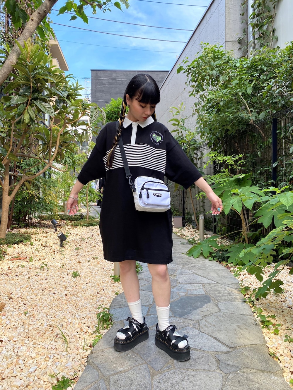 ブラック系のポロシャツ、ホワイト系のショルダーバッグを着用したレディースの夏コーディネートの2枚目の写真