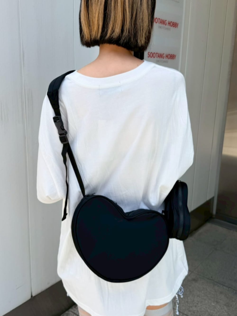 ホワイト系のTシャツ/カットソー、ブラック系のショルダーバッグ、ブラック系の水着を着用したレディースの夏コーディネートの7枚目の写真