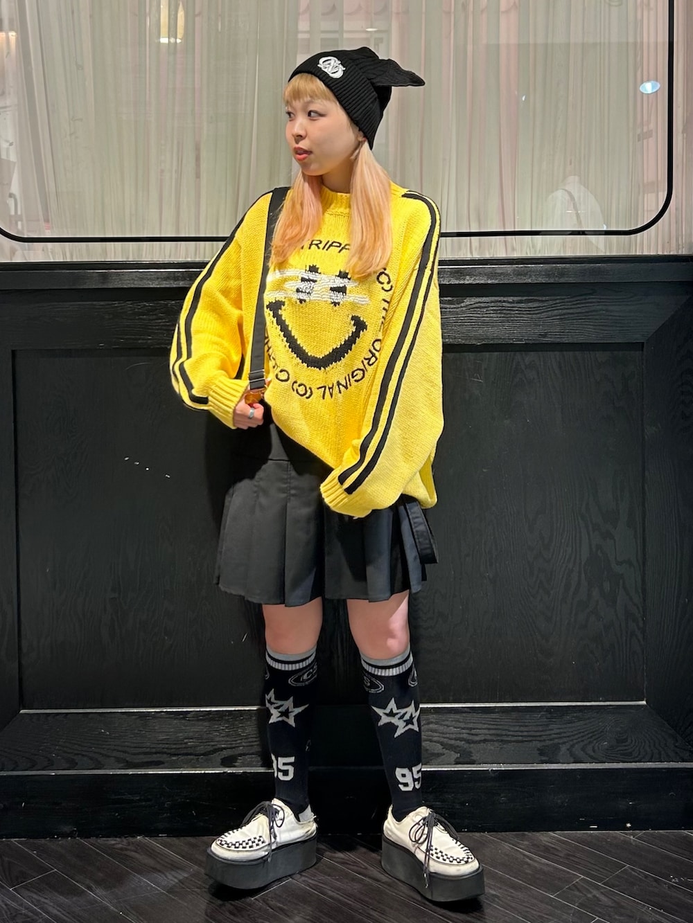 イエロー系のニット/セーター、ブラック系のスカート、ブラック系のニットキャップ/ビーニーを着用したレディースの秋コーディネートの4枚目の写真