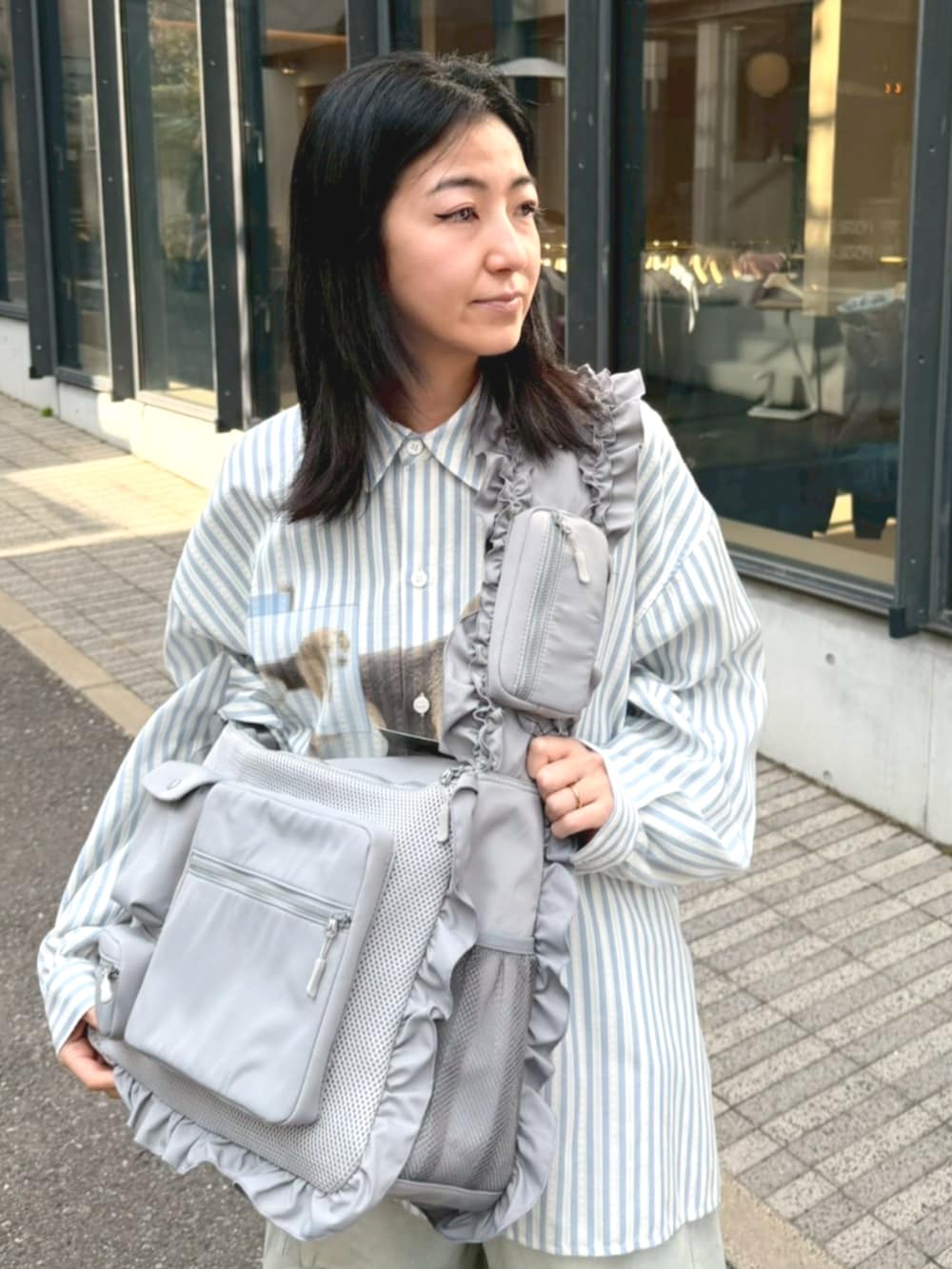 ブルー系のシャツ/ブラウス、グレー系のショルダーバッグ、ブルー系のデニムパンツを着用したレディースの冬コーディネートの4枚目の写真