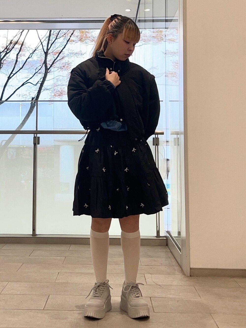 ブラック系のスカート、ブルー系のニット/セーター、ブラック系のダウンジャケット/コートを着用したレディースの冬コーディネートの2枚目の写真